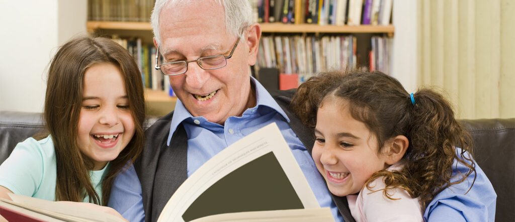 Grandfather reading book to granddaughters