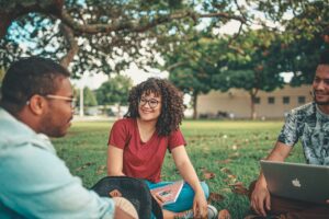 students sitting in grass discussing classwork